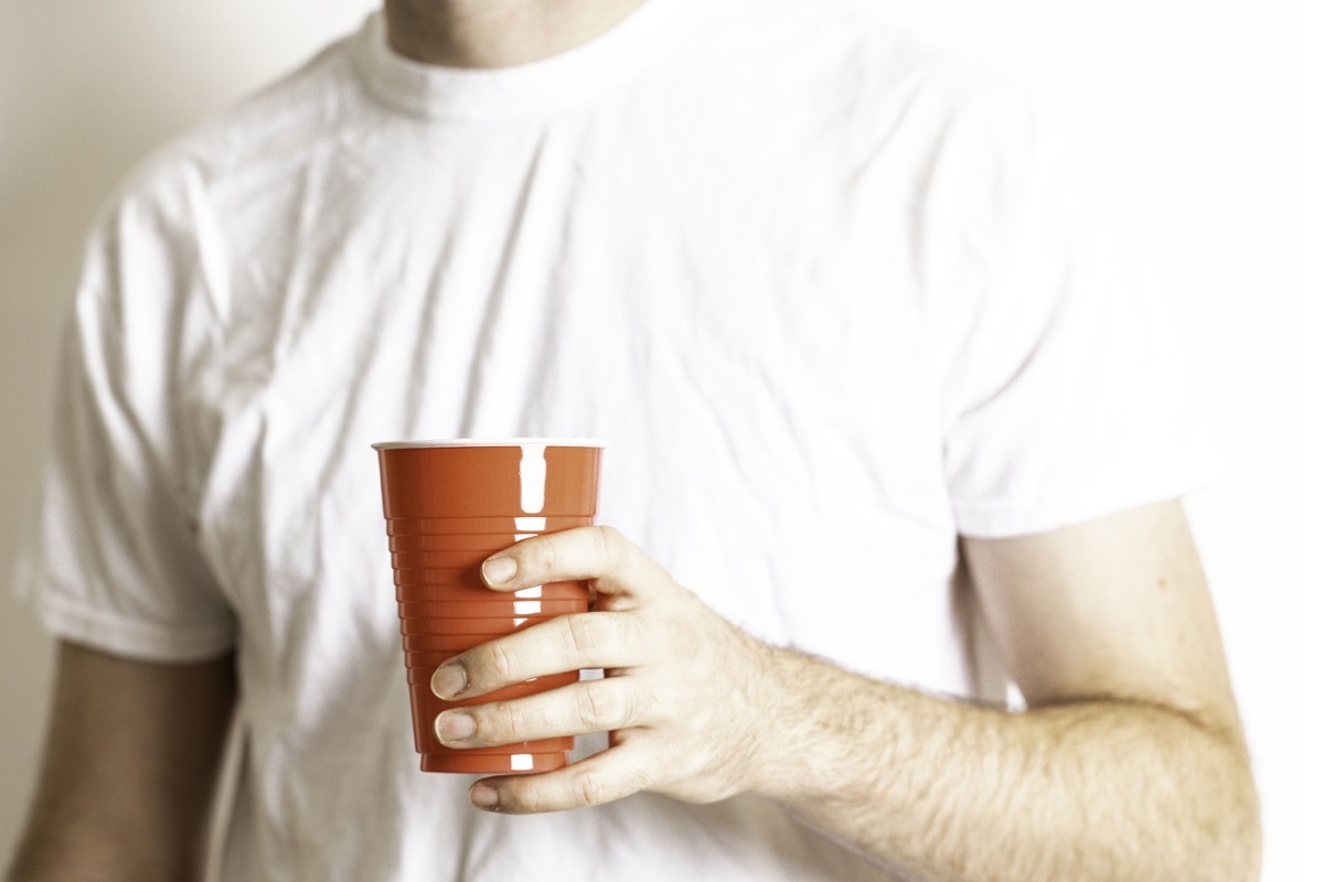 Person holding a red disposable party cup on a white background