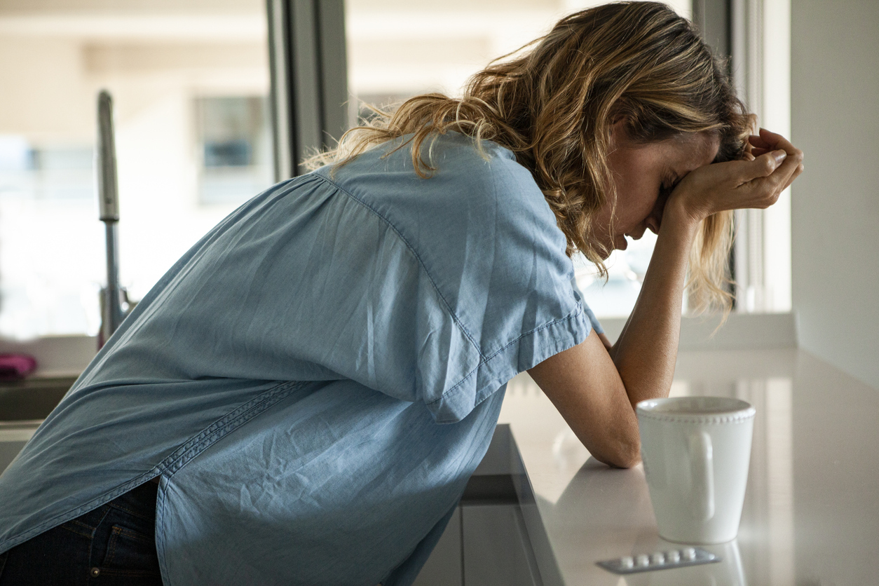 Woman with a headache and medication beside her. 