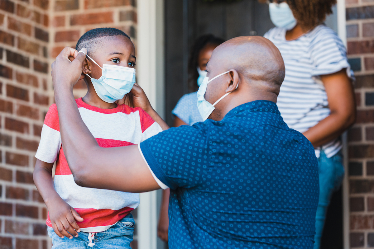 Father helps son put on protective face mask