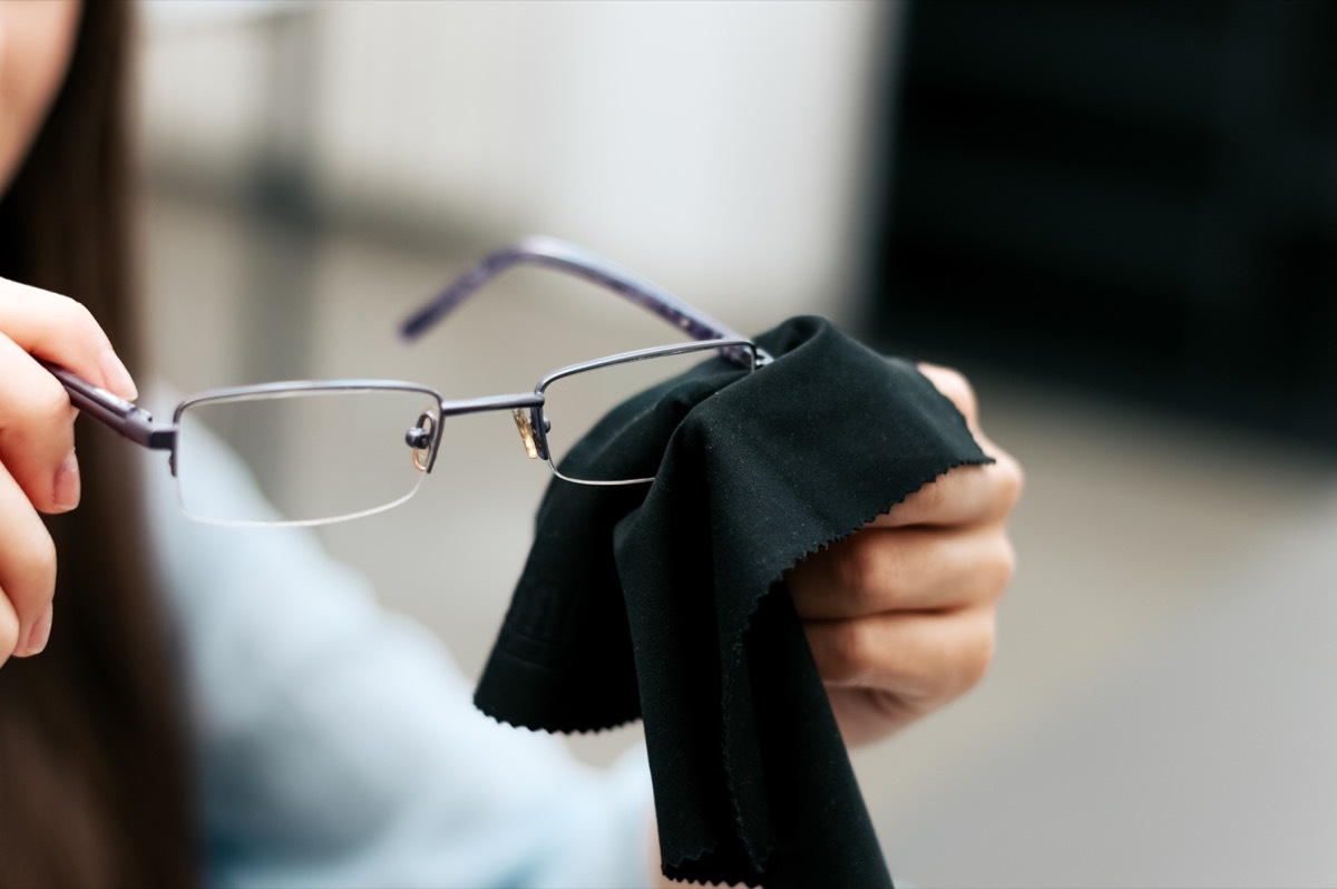 woman cleaning eye glasses with black cloth