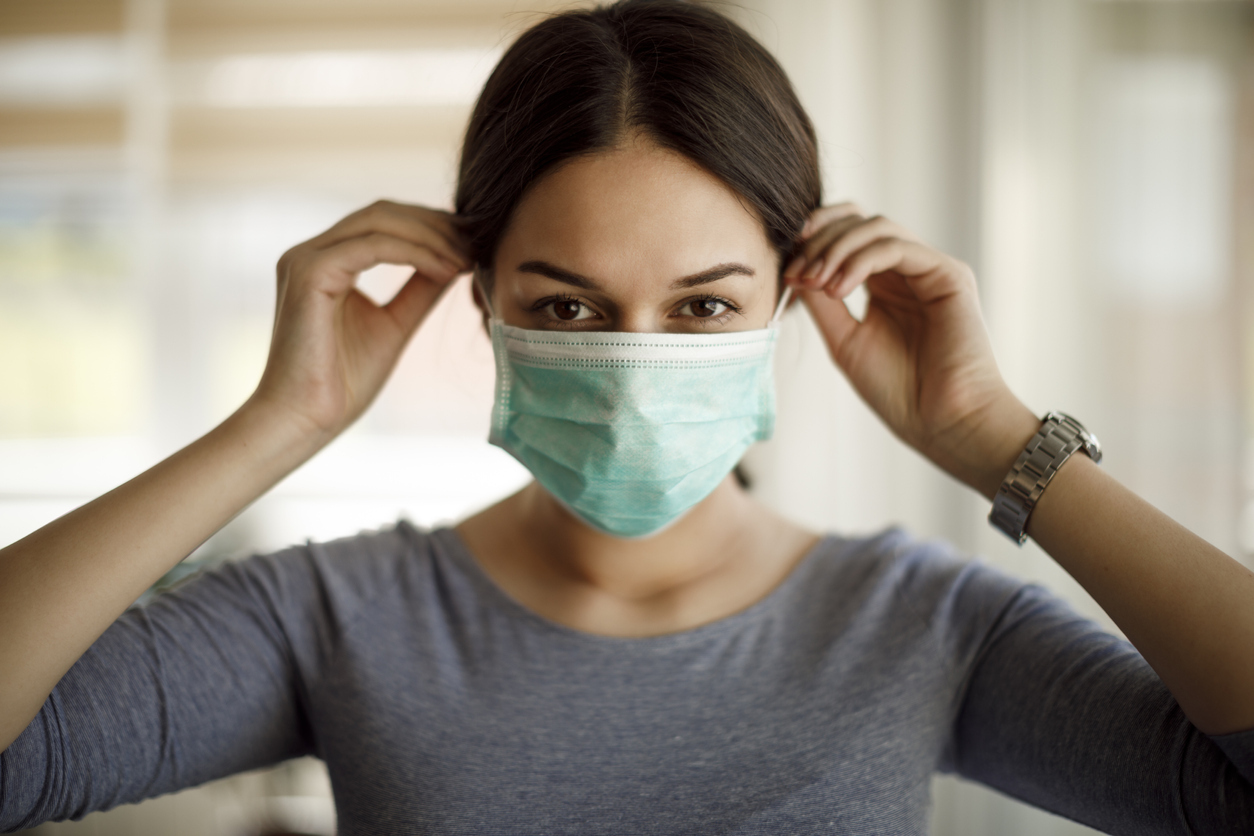 A young woman putting on a protective mask