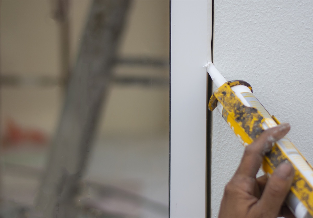 Repairman's hand installing the windows with gun silicone. closeup