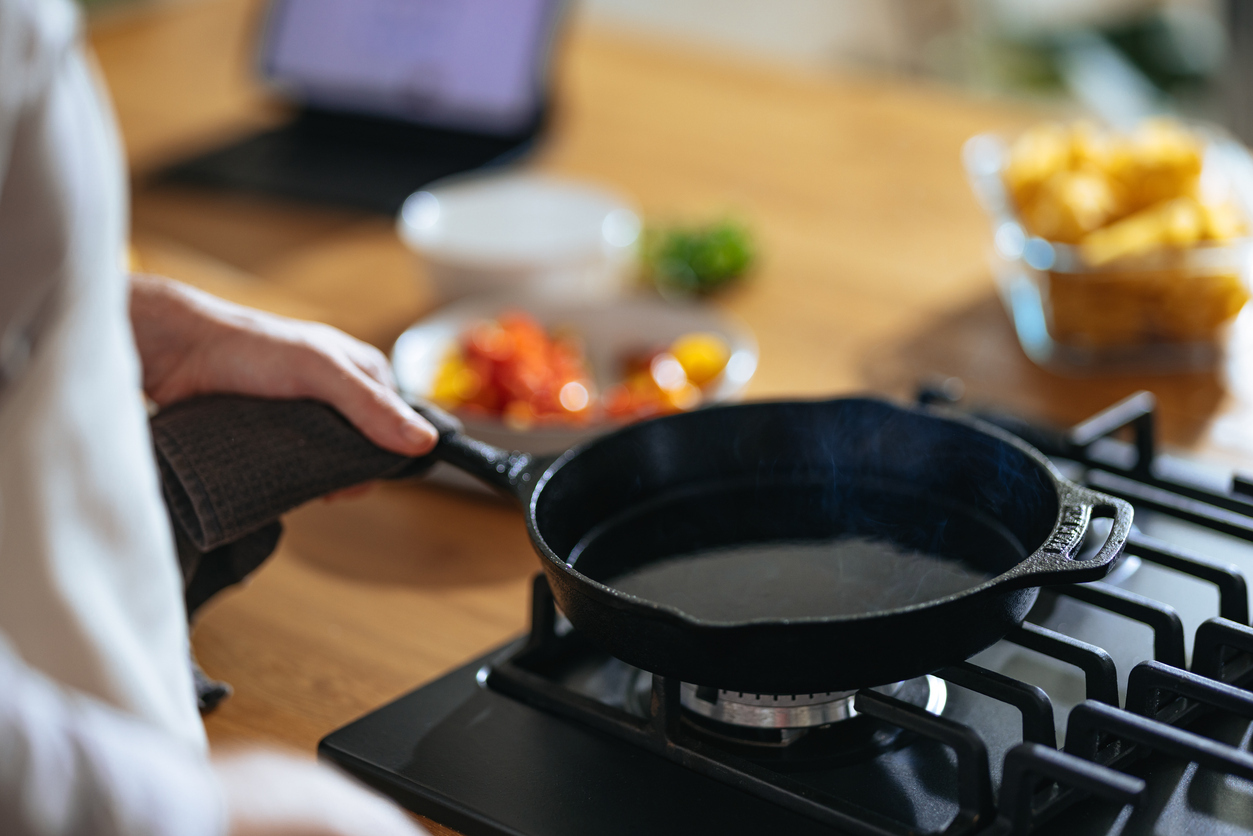 A close up of someone seasoning a cast iron skillet on the stovetop