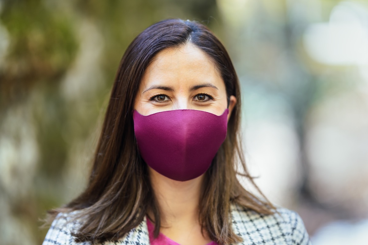 Mid adult woman smiling behind with colorful mask