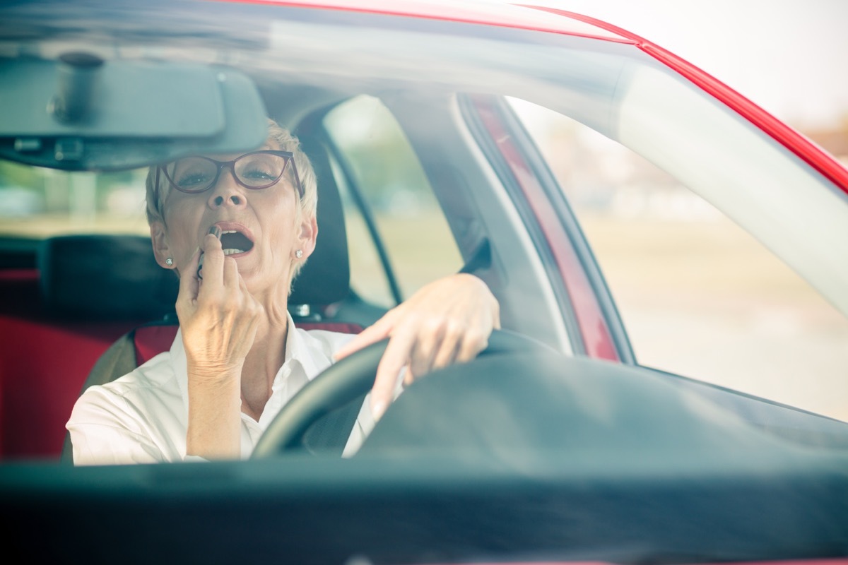 woman stopped at red light with short grey hair puts on lipstick, skin cancer facts