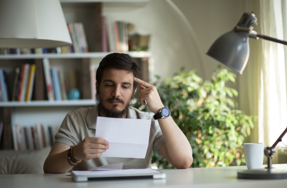 Angry stressed businessman opening envelope reading bad news in letter