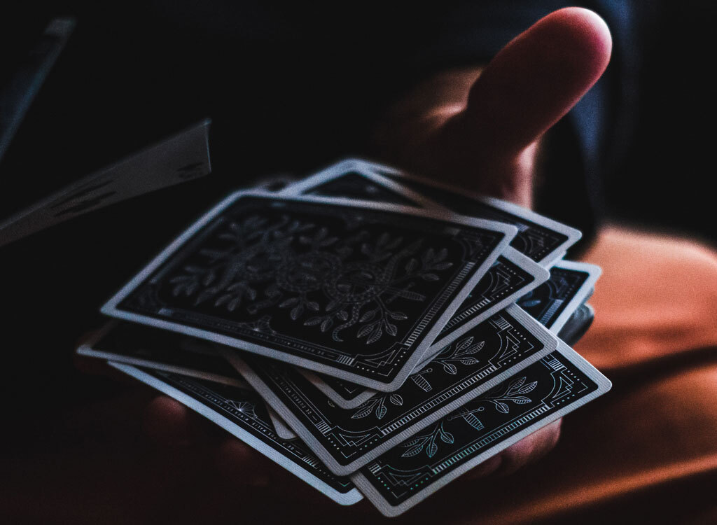 Man holding playing cards dark