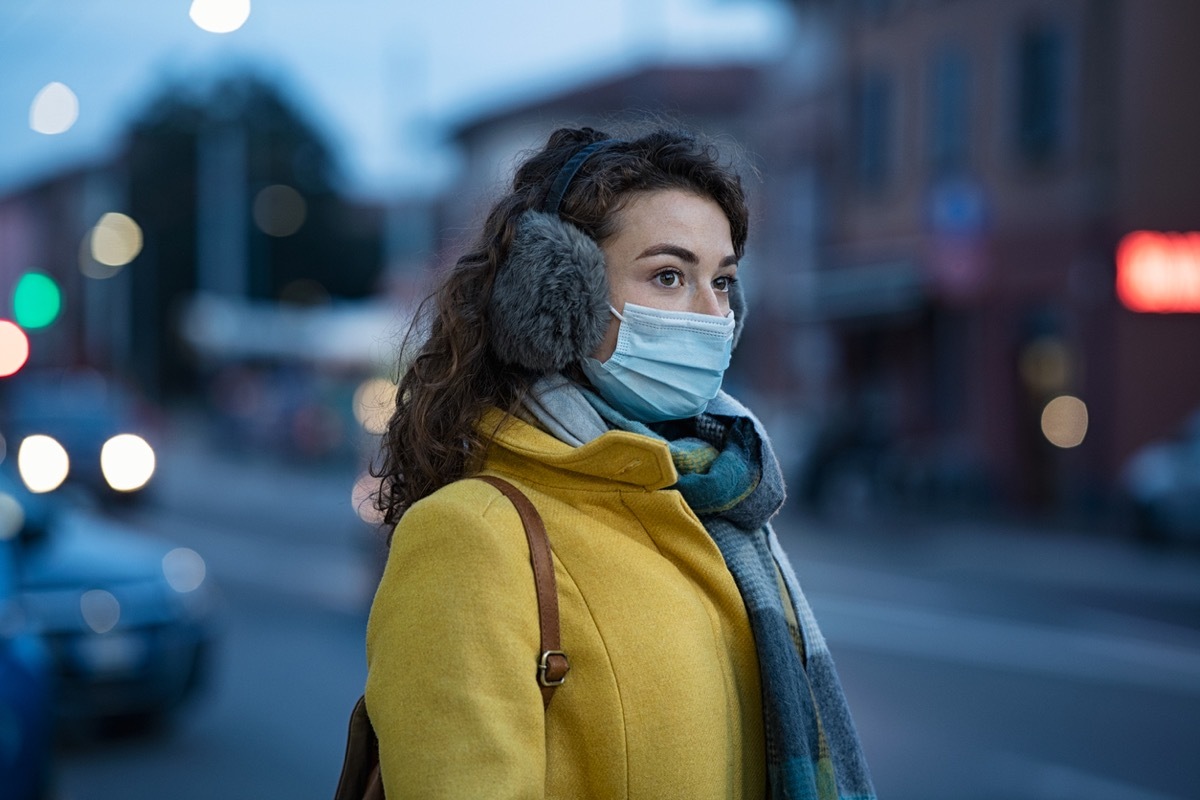 woman with a face mask and ear muffs standing outside in the winter