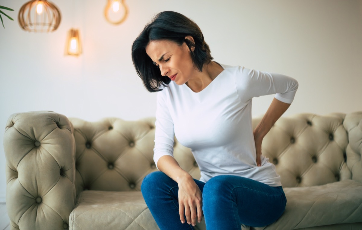 Woman holds her belly with hands with closed eyes due to pain