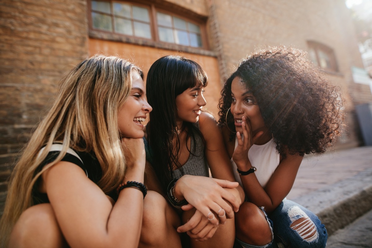 friends gossiping while sitting on a sidewalk