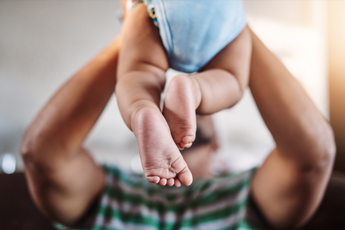 Shot of an unrecognizable little boy being lifted up by his dad while being seated on a sofa at home during the day