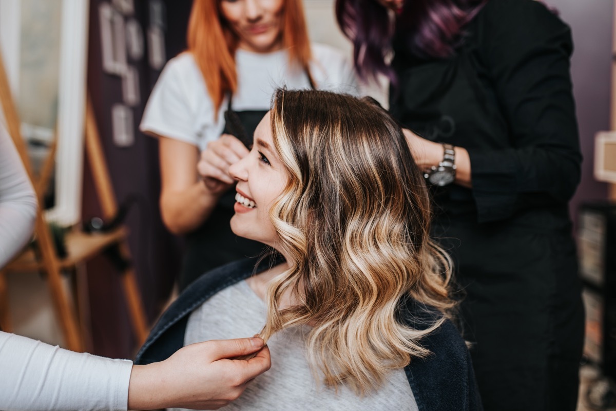 Beautiful hairstyle of young woman after dyeing hair and making highlights in hair salon.