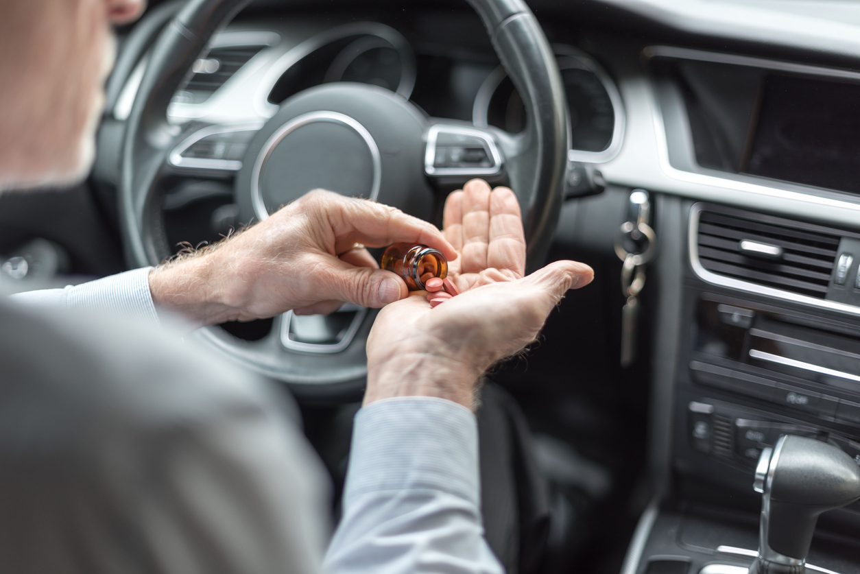 Man taking medicine before driving his car