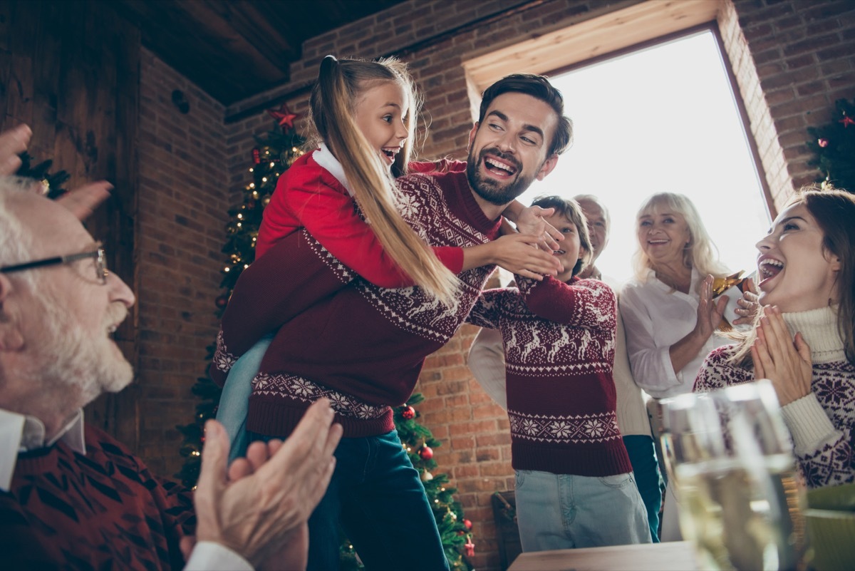 Girl getting on her father's back for a piggyback ride on Christmas