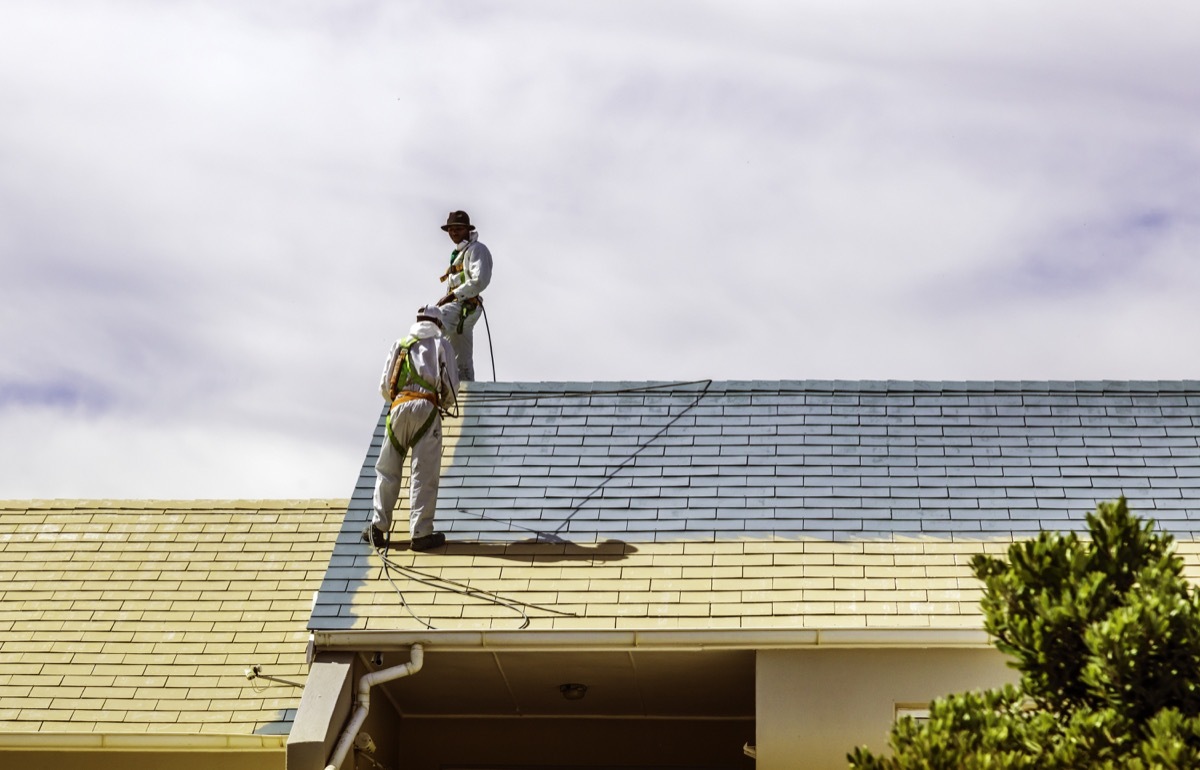 two men painting a roof