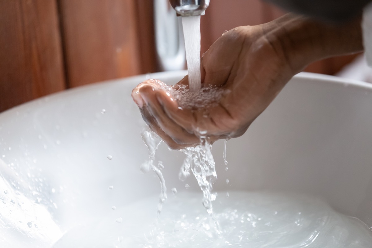 Close up view man hand gathering clear water pouring from faucet into the human palm, concept of personal hygiene and morning routine, global climate warming and worldwide water crisis problem