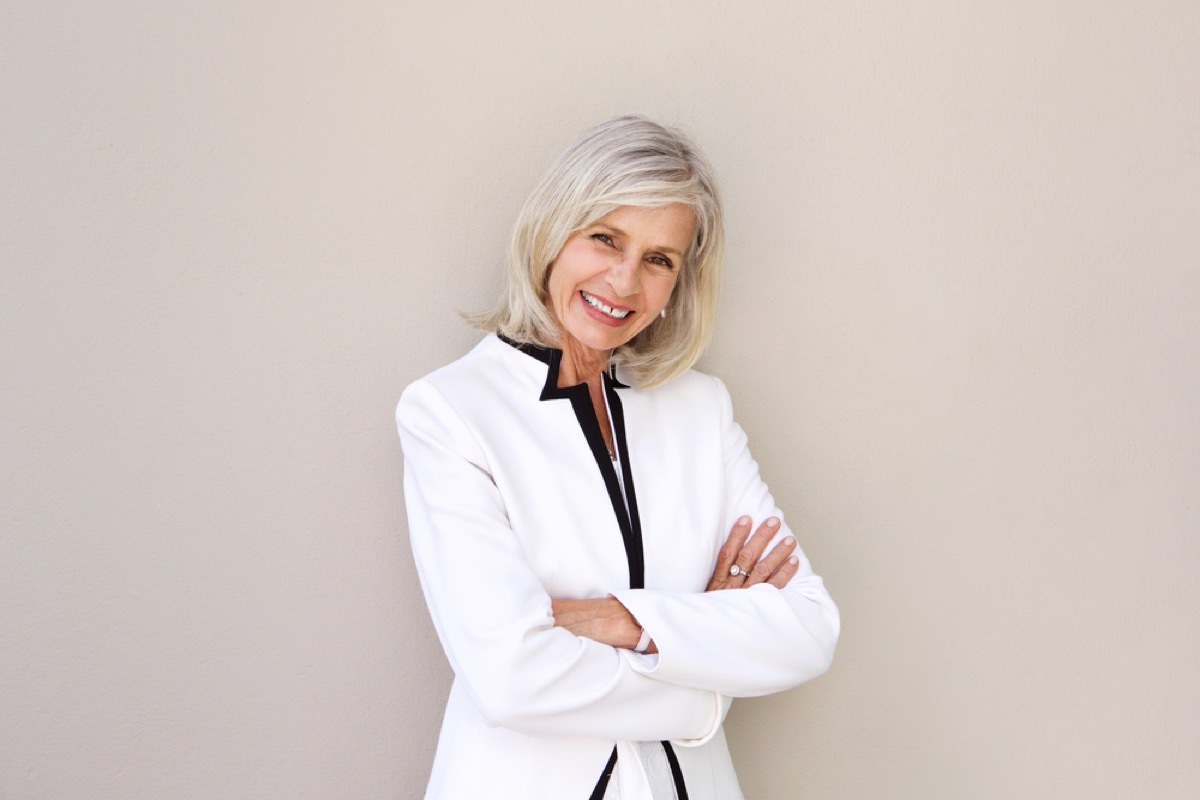 confident older woman with crossed arms standing outside, look better after 40