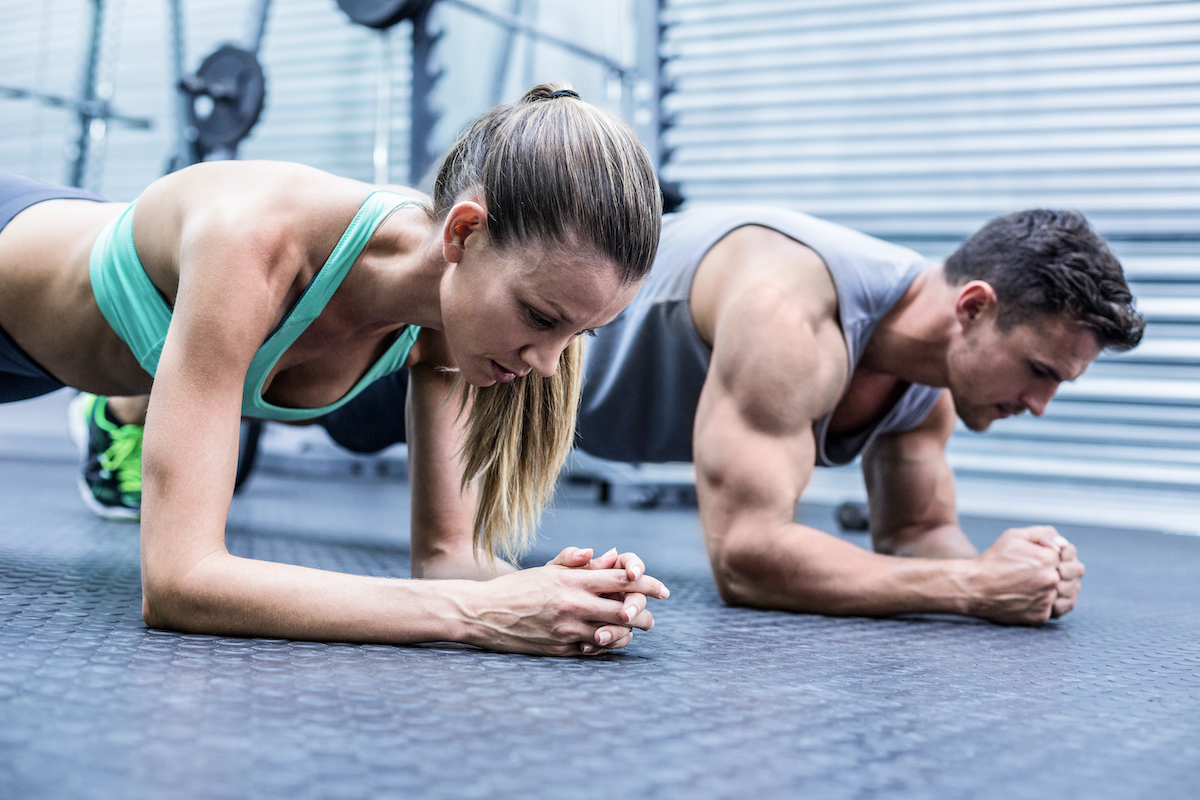 Side view of a muscular couple doing planking exercises