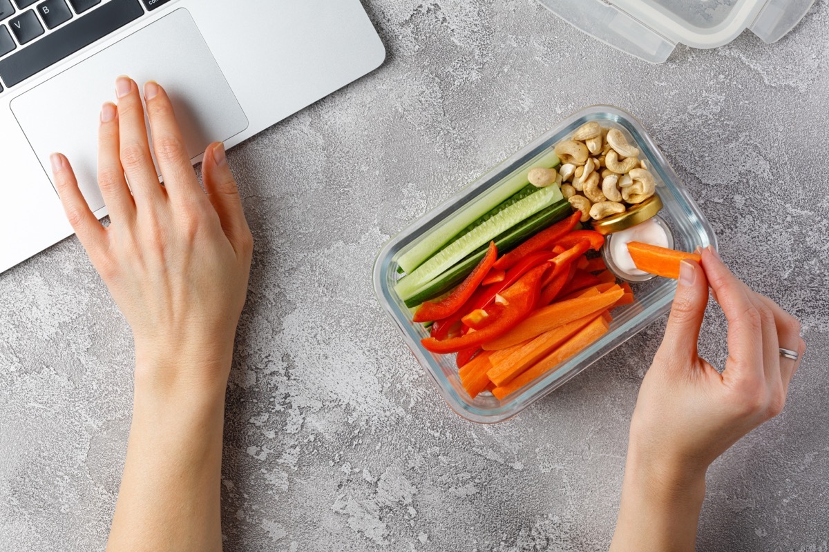 Snacking at work. Woman eating healthy snacks at work. Vegetable diet snacks. Glass container