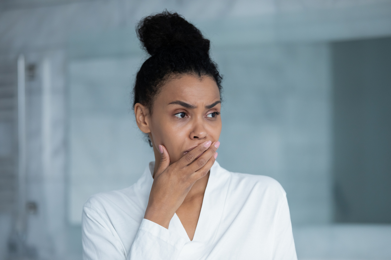 Woman feeling unwell with hand on her mouth. 