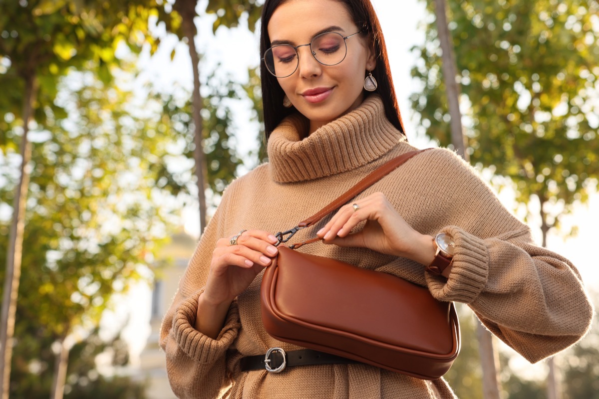 Fashionable young woman with stylish bag on city street