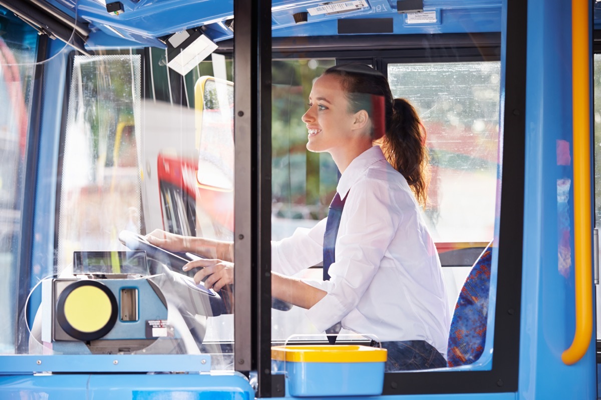 Young woman driving a public transportation bus