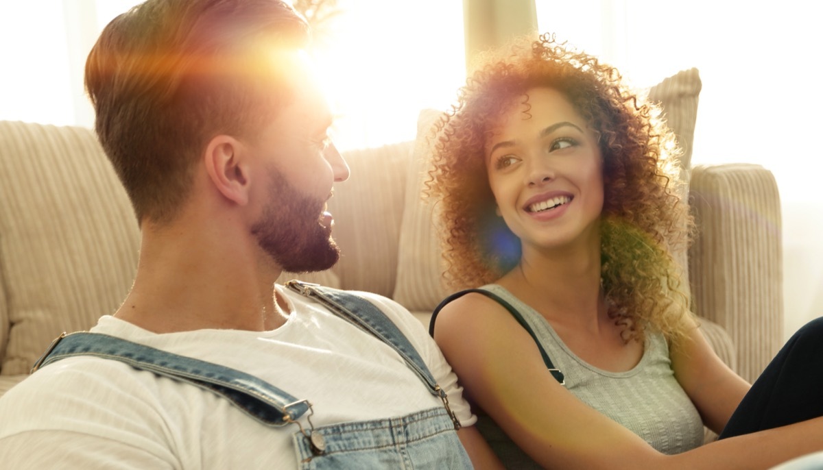 Young multicultural couple sitting on floor talking in the sunshine