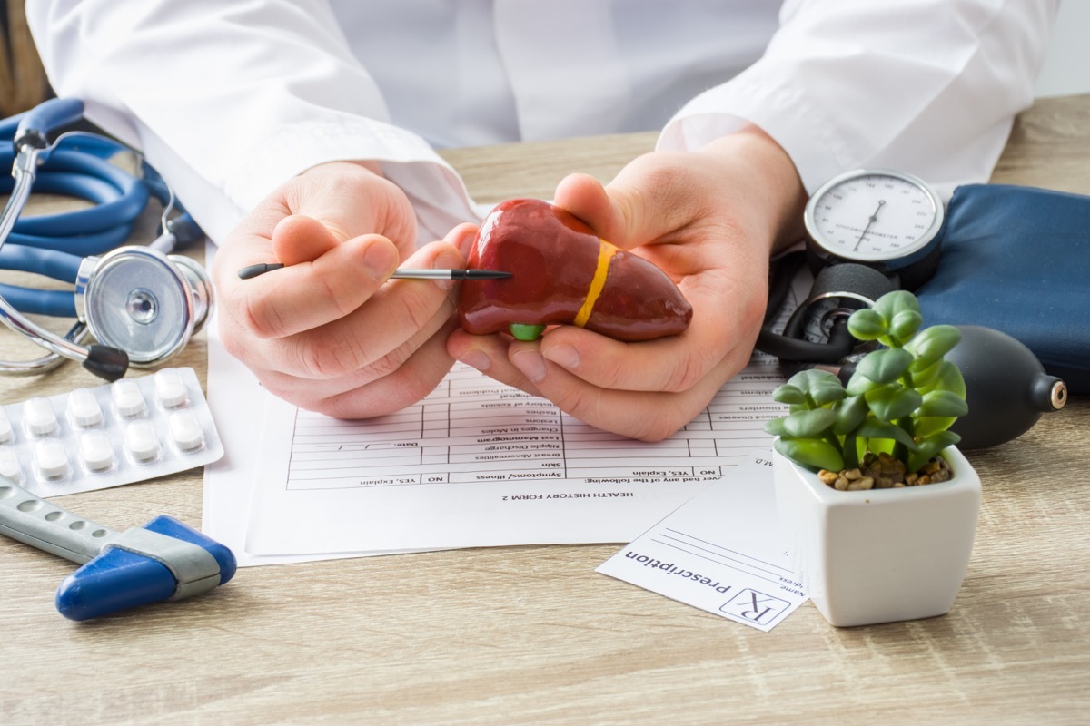 At doctors appointment physician shows to patient shape of liver with focus on hand with organ. Scene explaining patient causes and localization of diseases of liver, hepatobiliary system, gallbladder