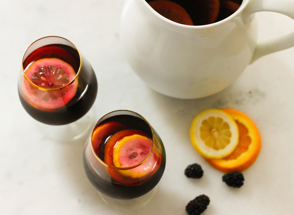 Cups of poured Carrabba's blackberry sangria with a pitcher ready to serve