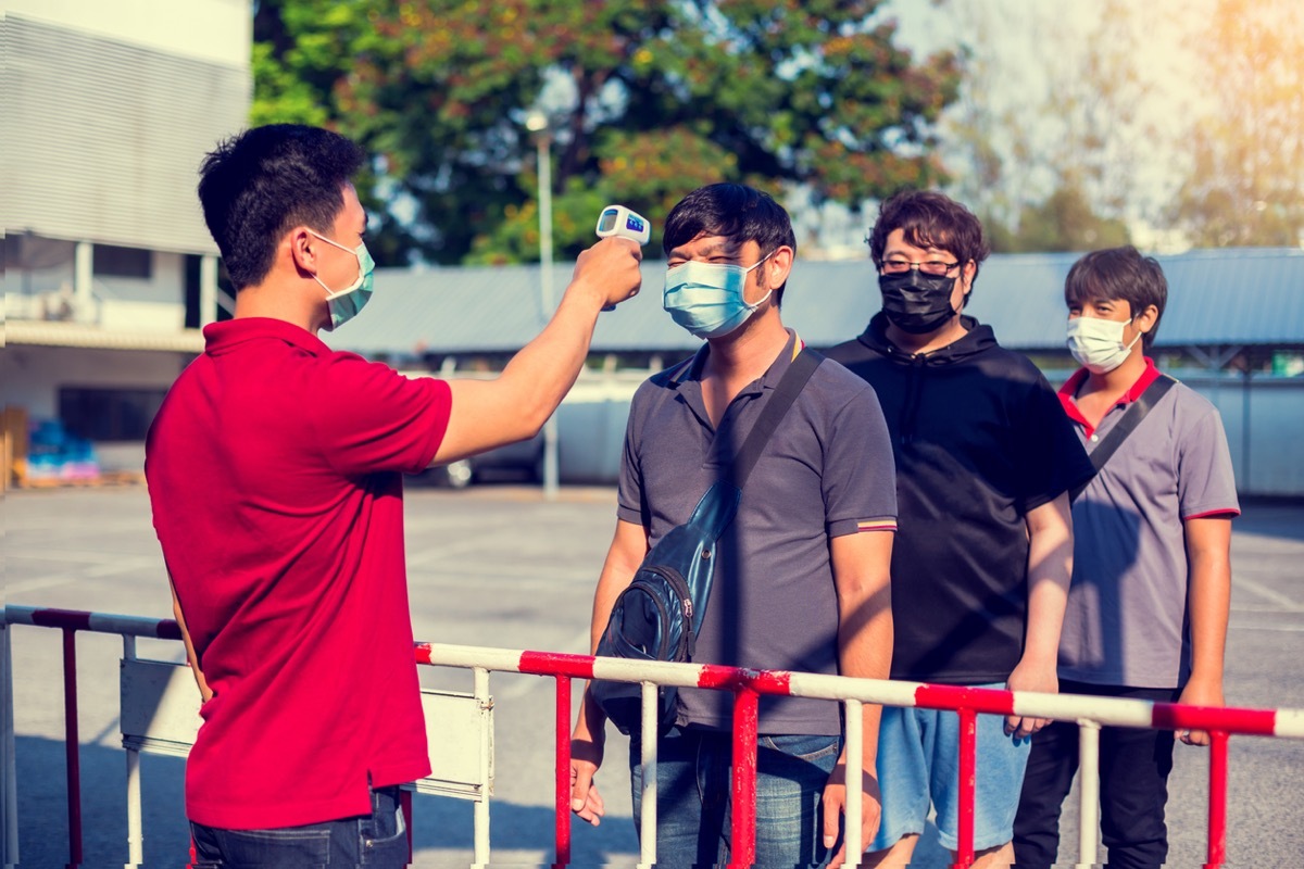 Staff check fever by digital thermometer before entering buildling