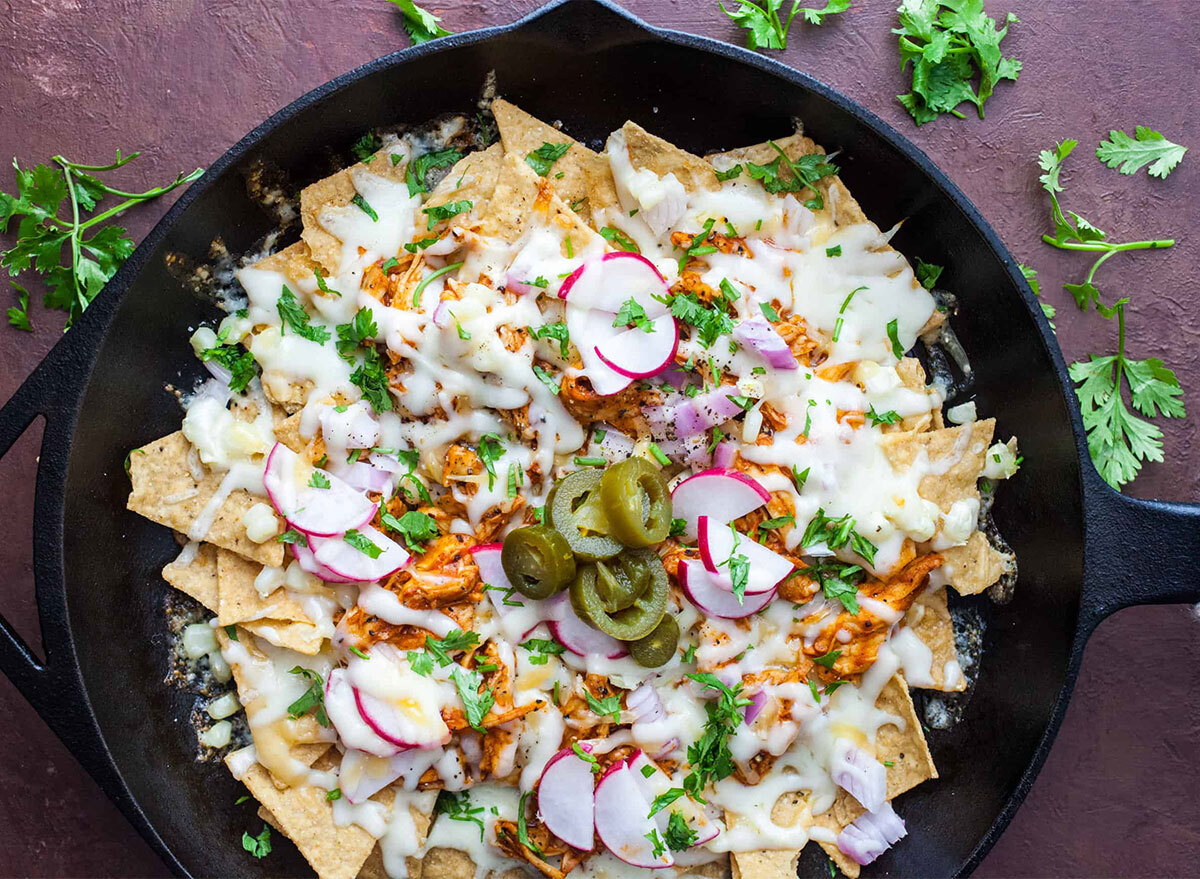 pan of nachos topped with cheese and radishes in a skillet