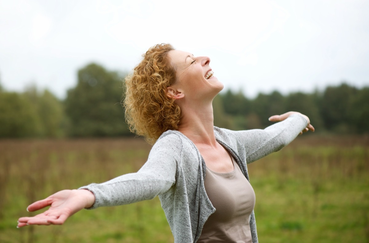 Woman smiling and dancing outside. 