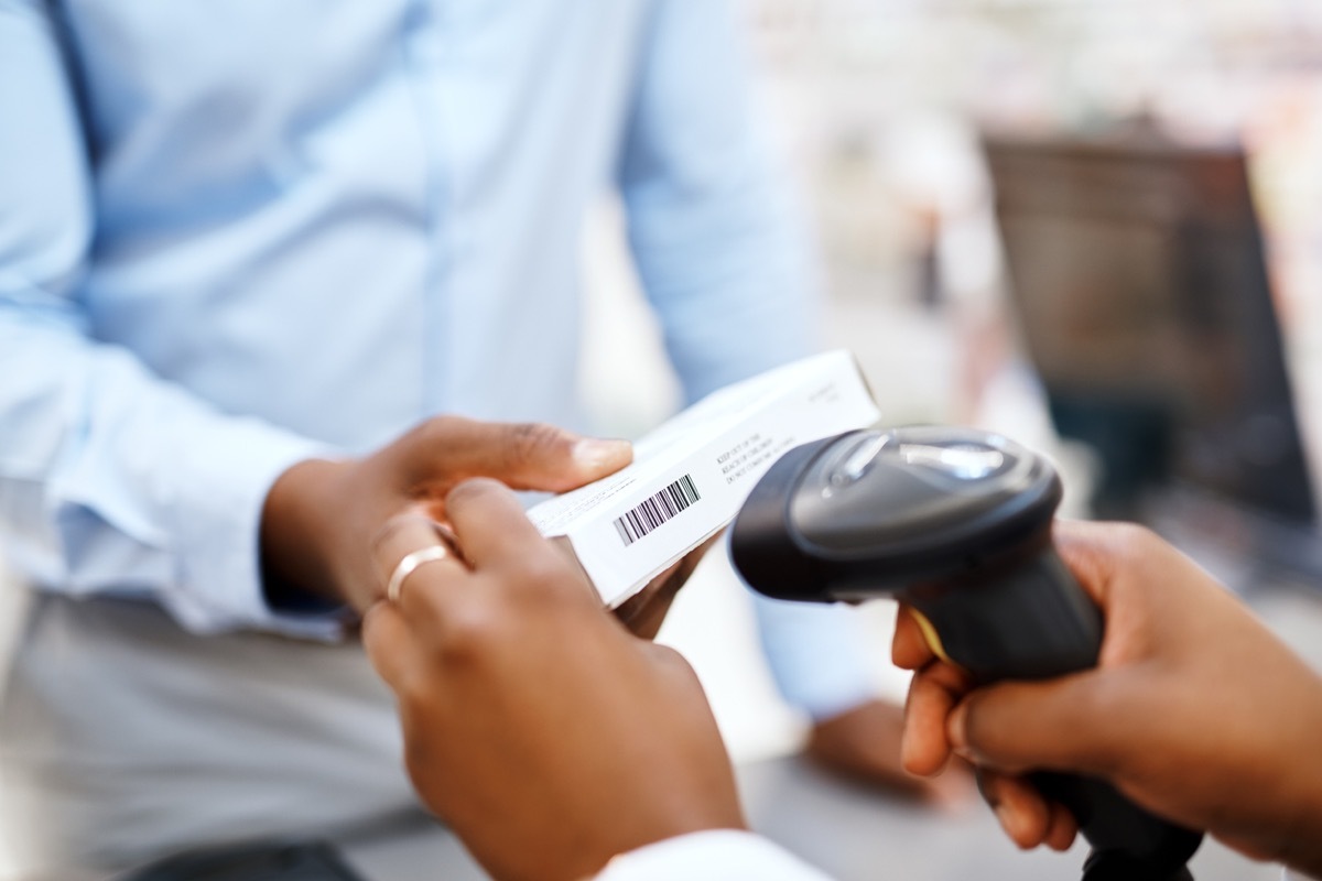 Closeup shot of a pharmacist scanning a box of medication for a customer in a chemist