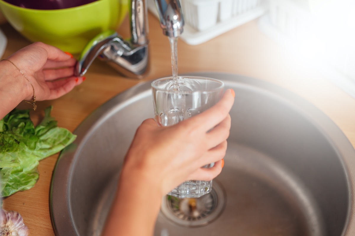 Woman hand's filling the glass of water.