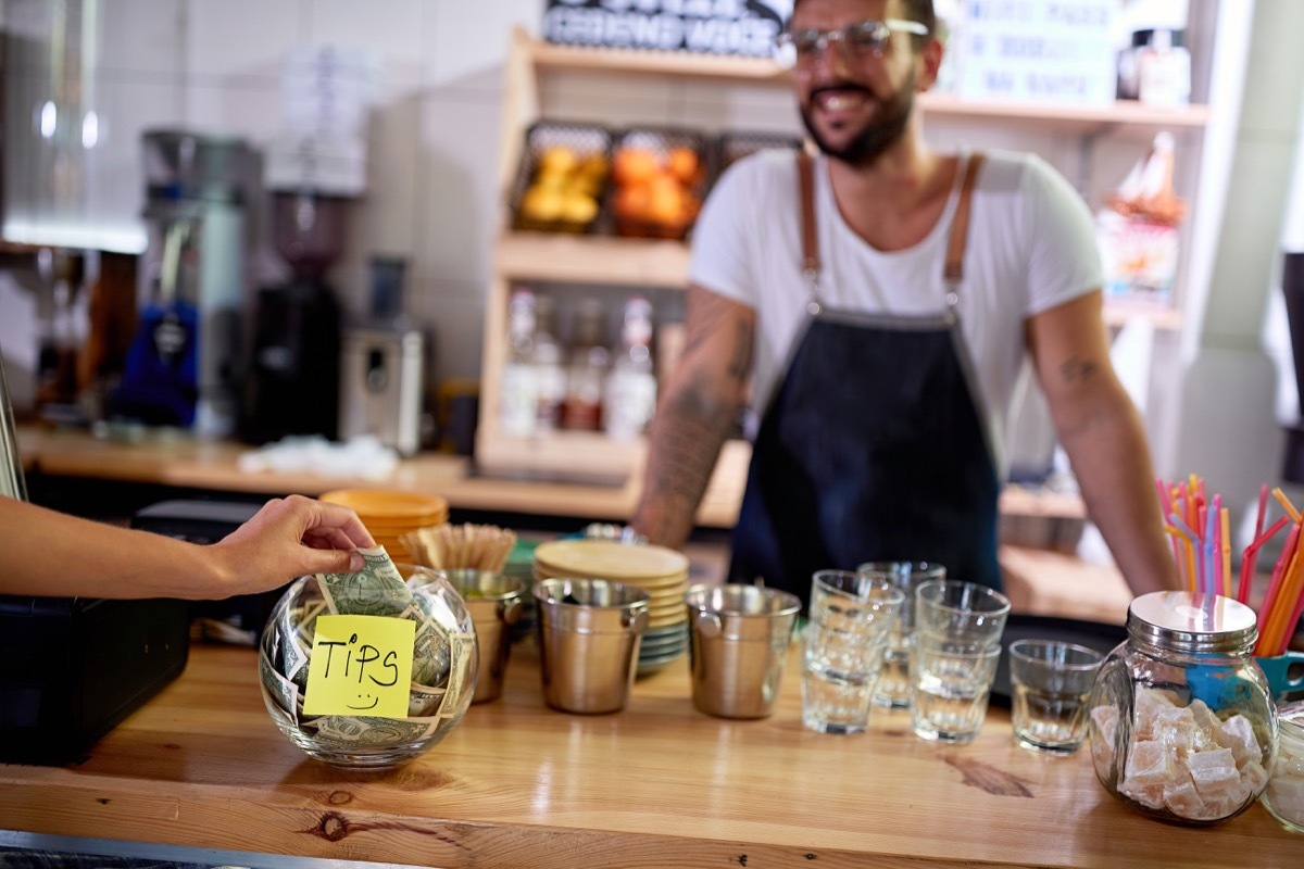 Person putting money in a tip jar at a cafe