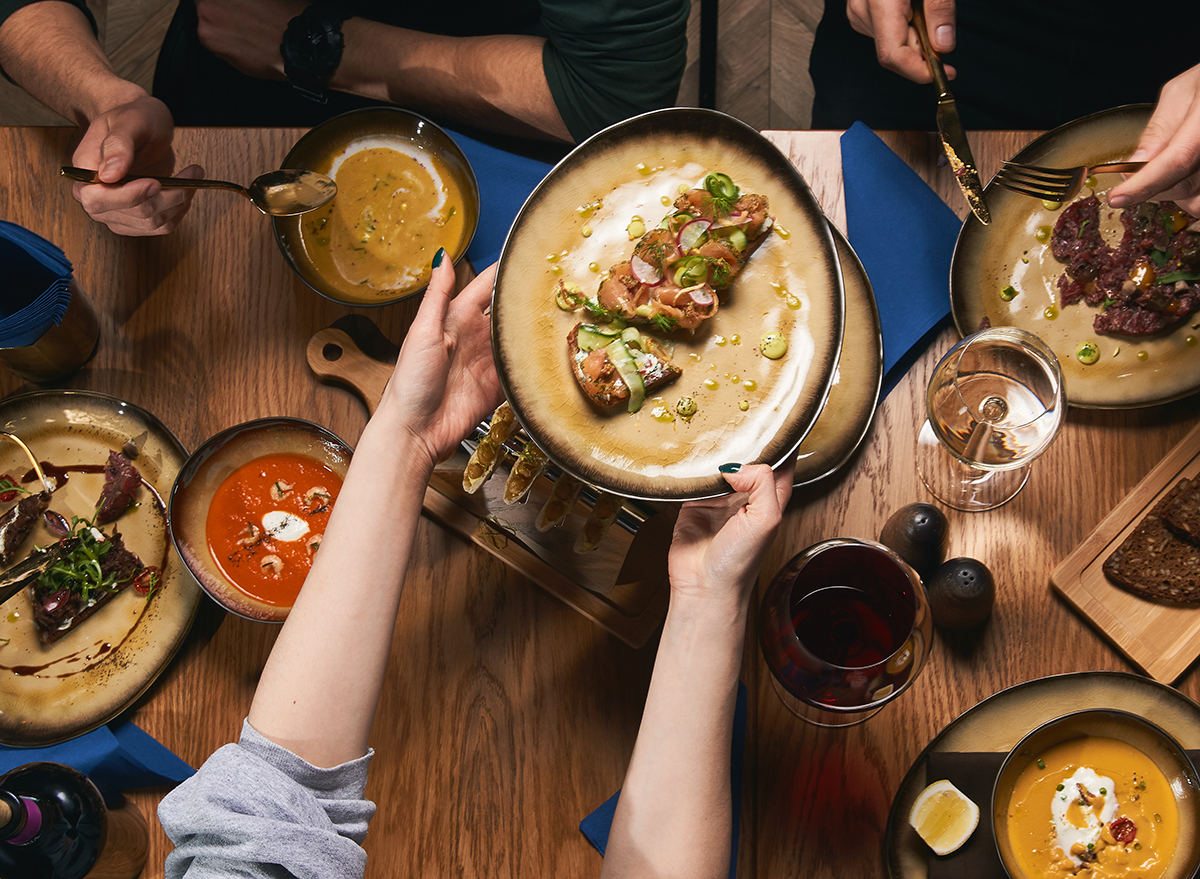 person passing plate of food to another person at dinner table