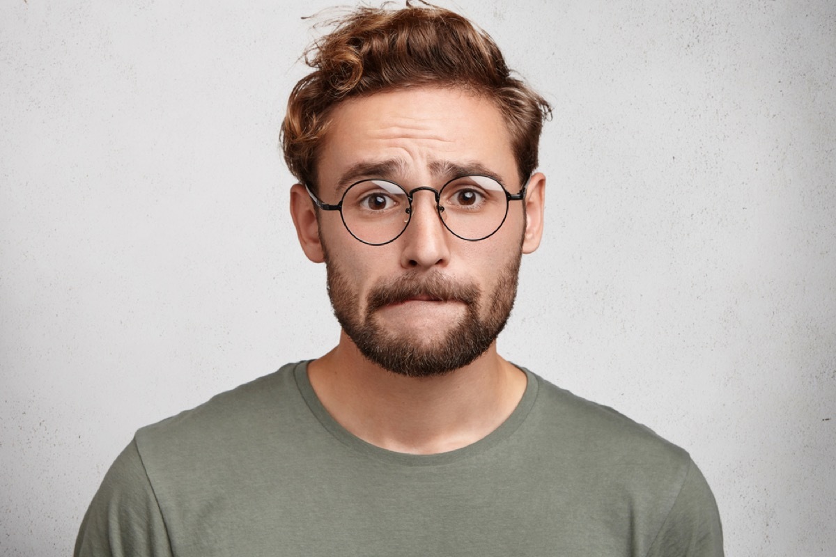 young white man with glasses biting cheek