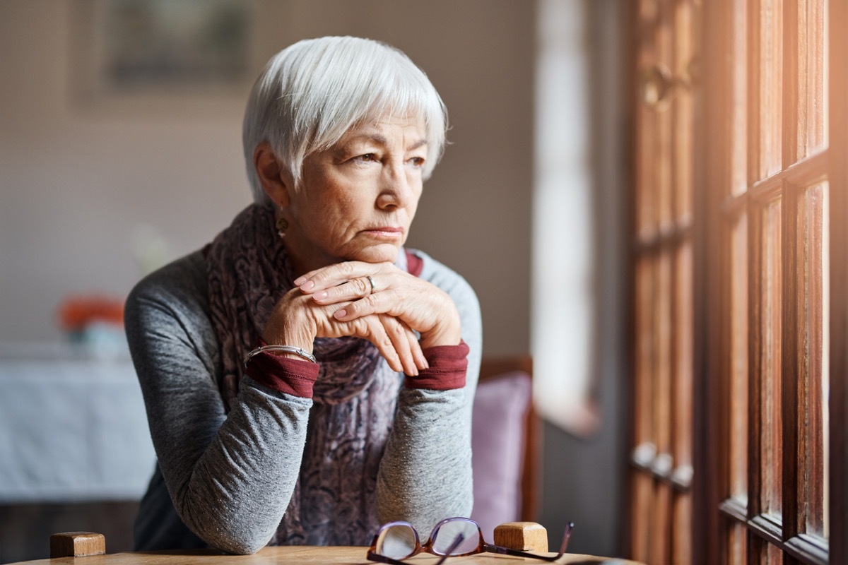 senior woman looking thoughtful as she stares out window