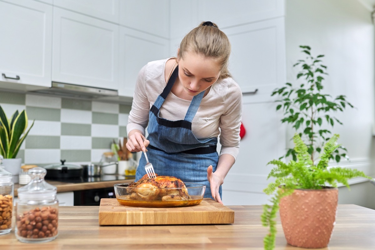 Woman cooking baked chicken at home in the kitchen. Homemade food, traditional food for the holidays, delicious eat at home concept