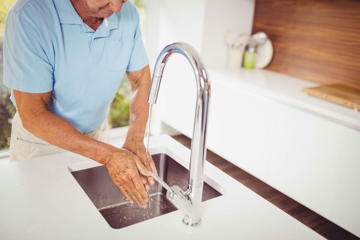 Mid section of senior man washing hands in the kitchen