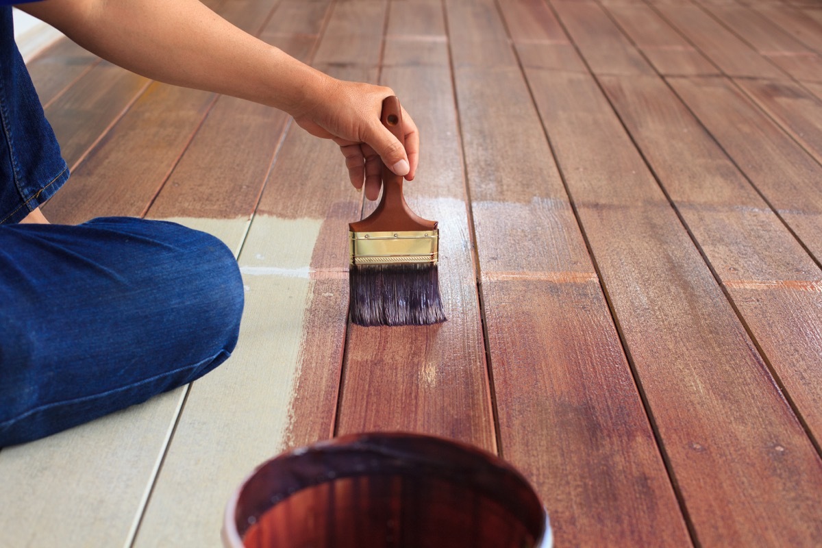 man painting floor with paintbrush