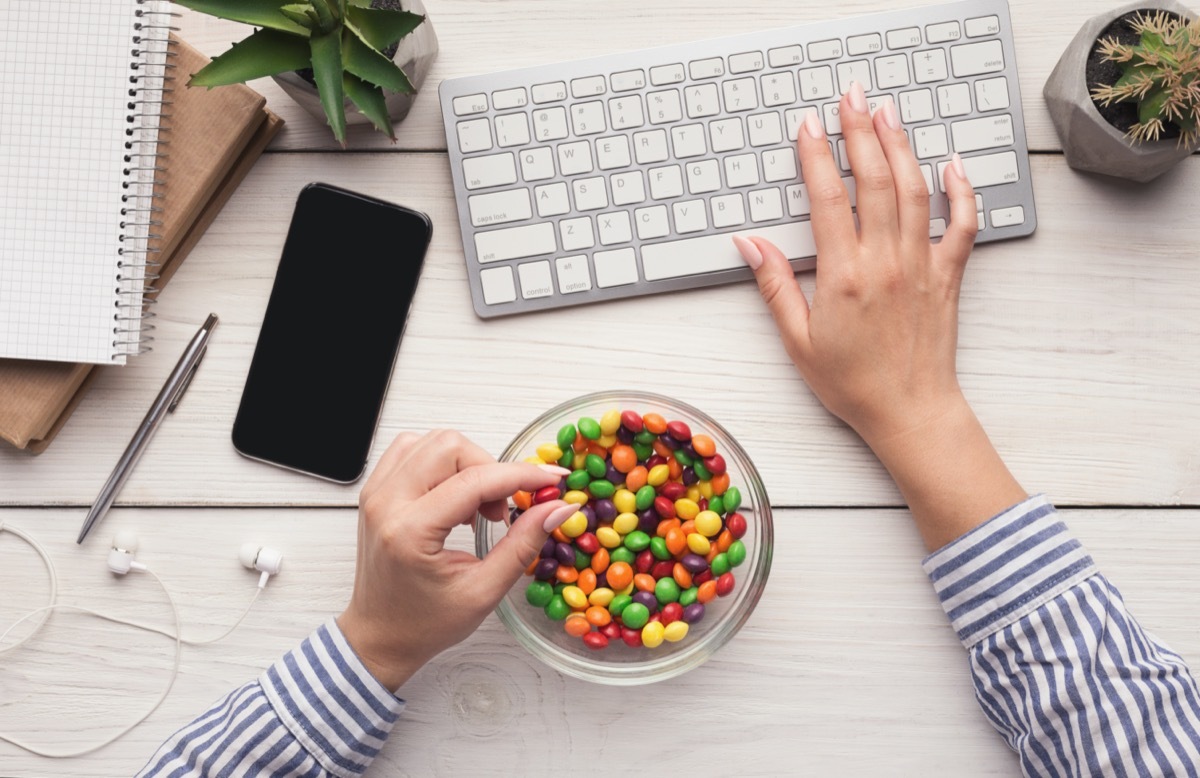 Work space with laptop, candies and woman hands