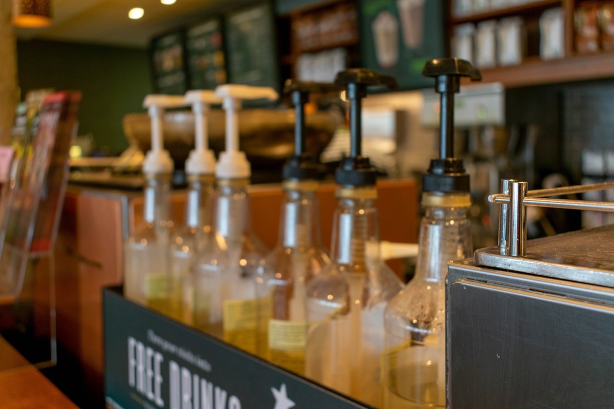 Durham, UK - 14th July 2019: Blurred photograph of Starbucks syrups with plastic lids and the counter in the background. Starbucks is a popular coffee chain across the world. Coffee café concept.