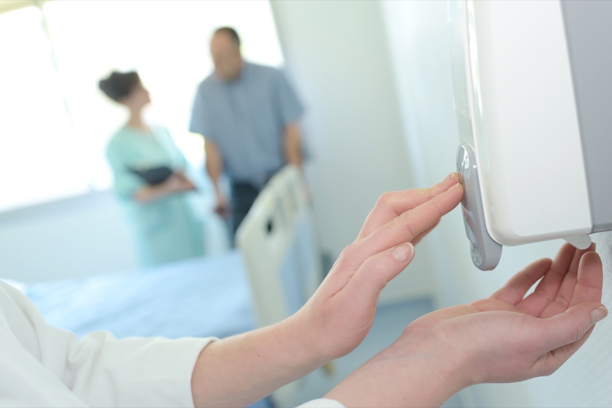 white hands pumping soap from wall-mounted soap dispenser 