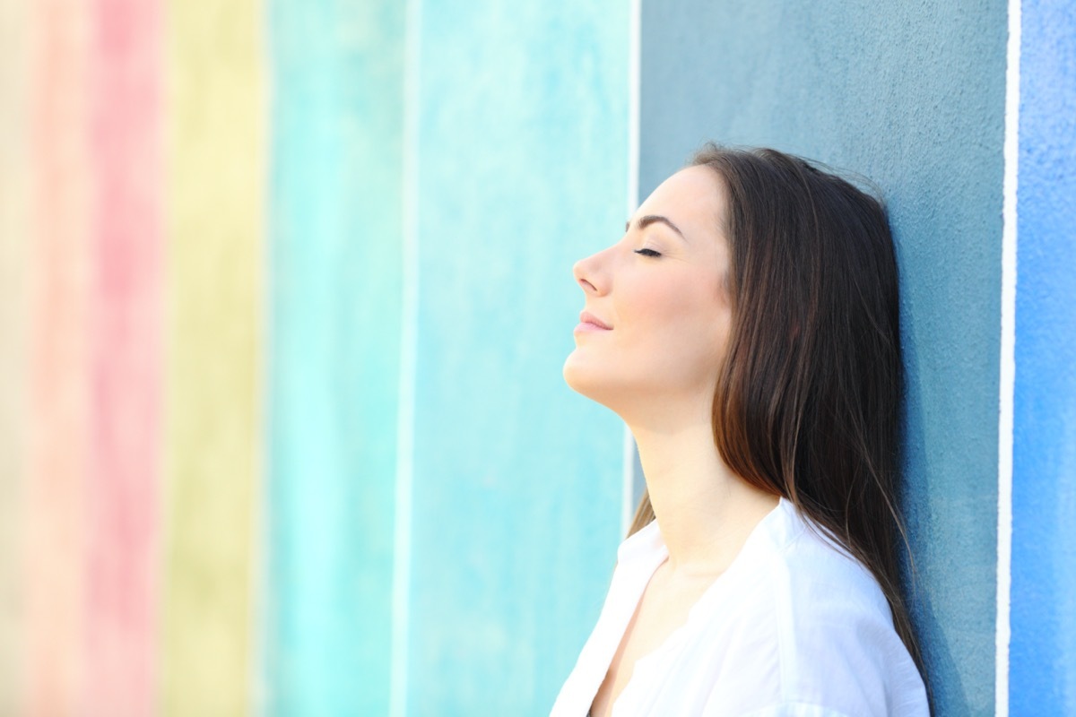 portrait of a relaxed woman resting leaning on a colorful wall in the street