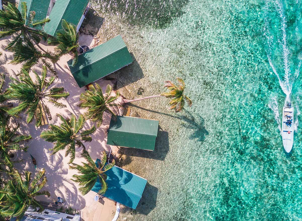 overhead aerial view of a boat and bungalows in crystal clear water