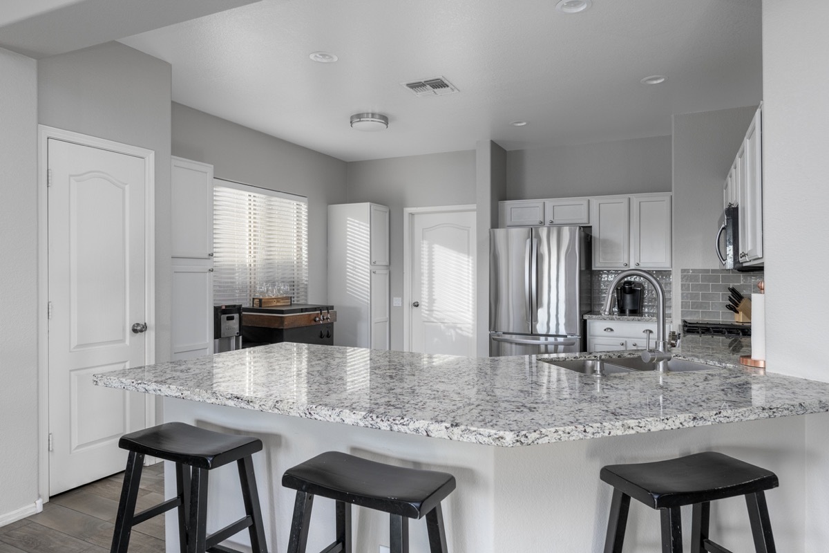 modern kitchen with granite counters and black stools