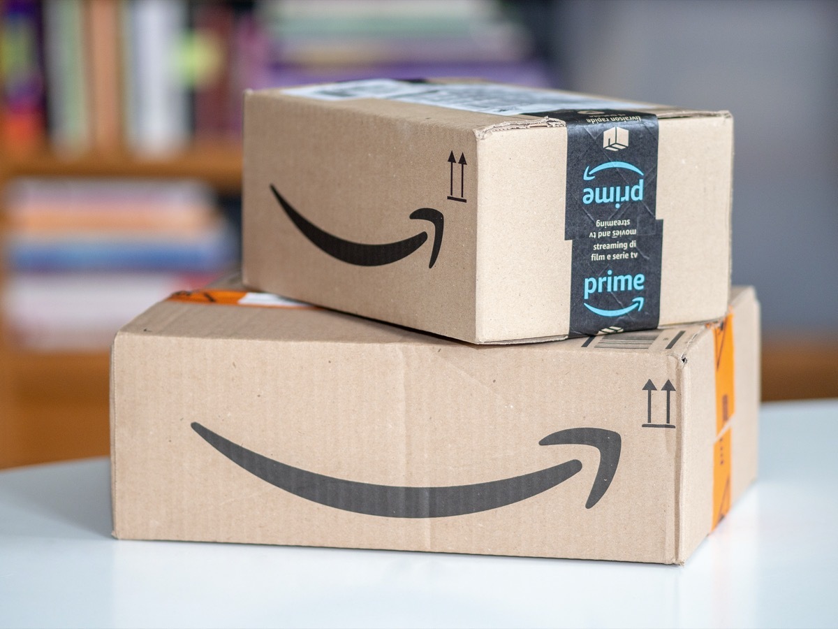 Amazon shipping box on a wooden floor in front of a door inside a house.