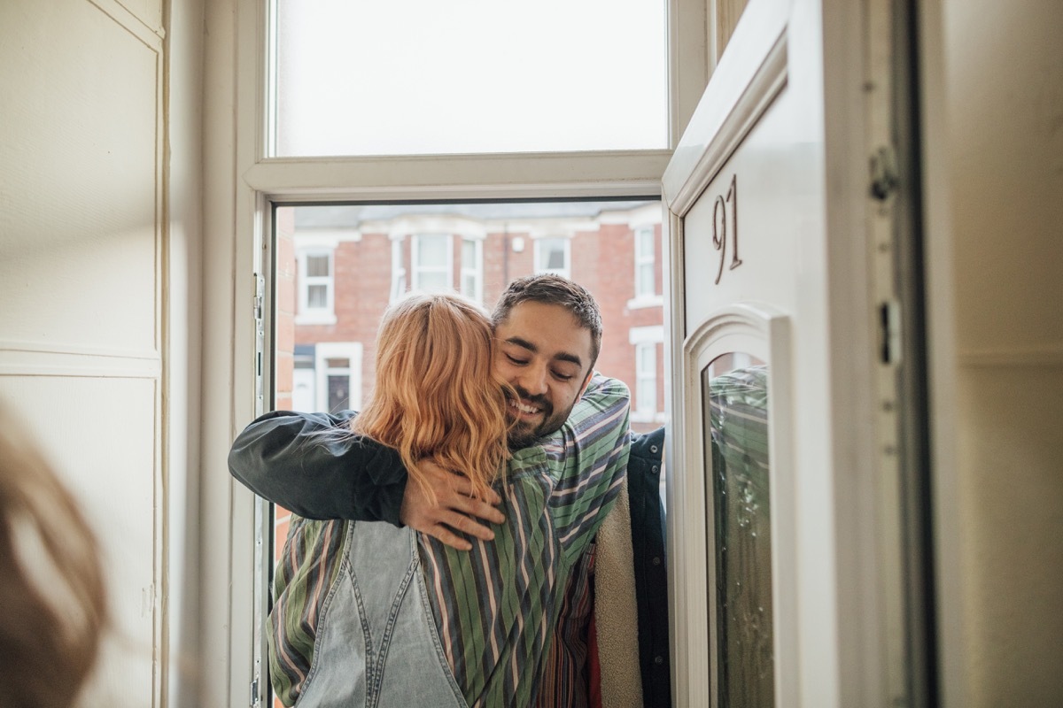 Friends arriving at a house for a social gathering. They are greeting each other at the front door.