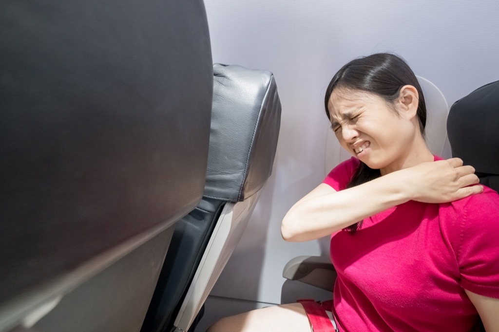 Woman has back pain on an airplane.